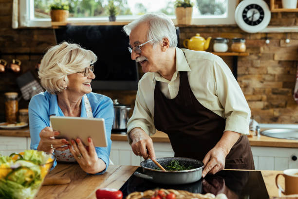 istock Happy senior couple talking while cooking and using touchpad in the kitchen. 1215986146