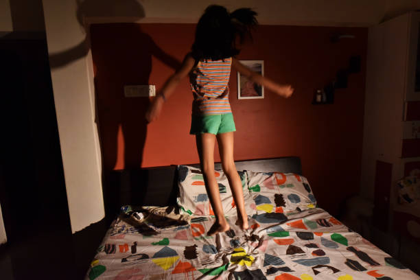 istock Girl jumping over bed 1215990035