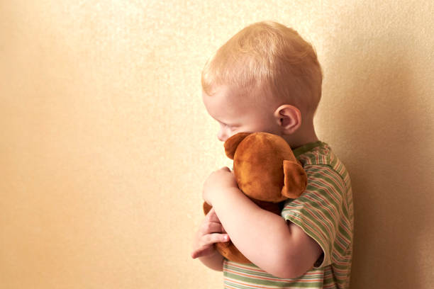 istock Little lonely boy hugs his teddy bear strongly. 1215991495