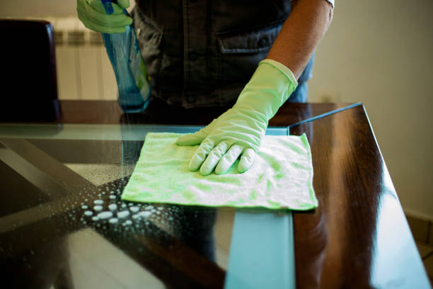 istock Middle-aged man disinfecting table glass due to virus corona. 1215993610