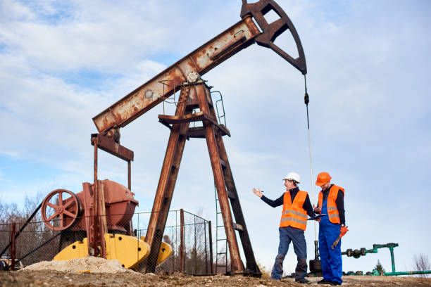 istock Oil workers in uniforms controlling progress work at local oil pump station on sunny day 1215993819