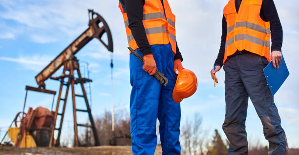 istock Oil workers in uniforms controlling progress work at local oil pump station on sunny day 1215993824