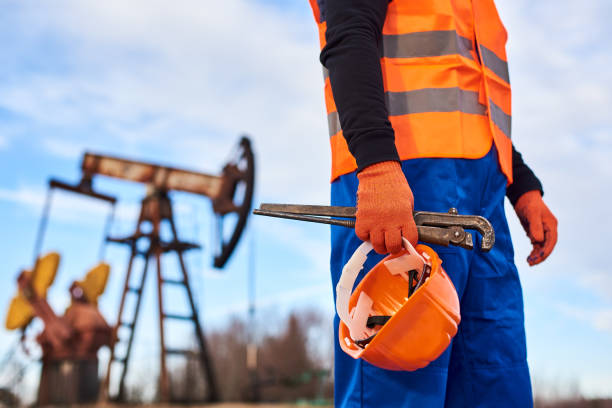 operaio dell'olio in uniforme arancione e casco sullo sfondo il jack della pompa e il cielo blu. - drilling rig oilfield drill drilling foto e immagini stock