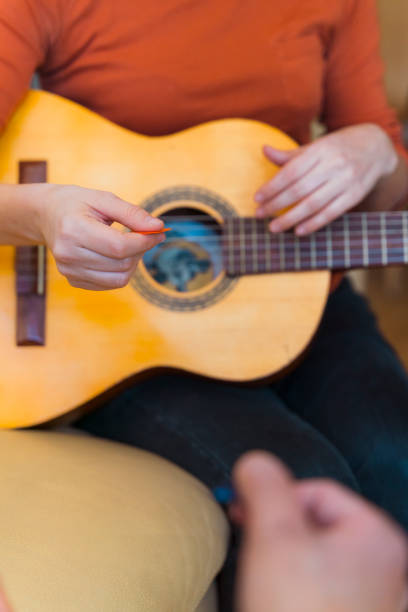 istock Detail of unrecognizable music student learning instruction to use a guitar pick. 1215994800