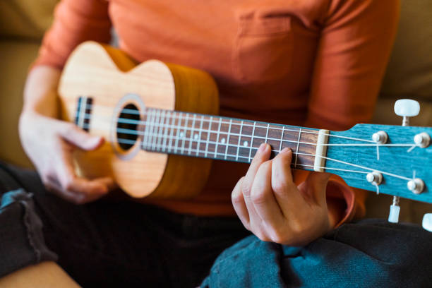 Detail of unrecognizable teacher and student of music lessons. Female professor close up explaining instructions of accurate ukelele chords position on guitar neck with bridge. Spanish guitar concept. ukulele stock pictures, royalty-free photos & images