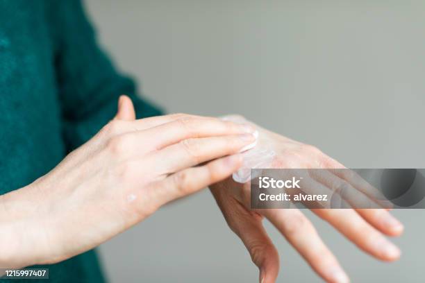 Woman Applying Hand Cream To Relieve The Dry Skin Caused By Hand Sanitizer Stock Photo - Download Image Now