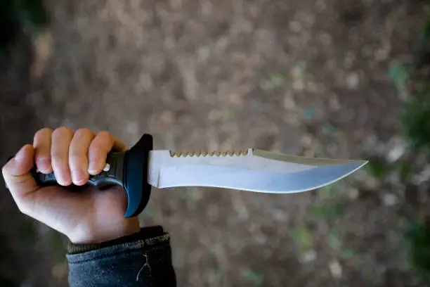 Close-up of Young Woman Holding a Large Knife as if Stabbing.