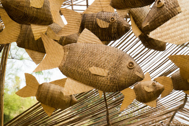 close-up tece decoração de peixe de madeira móvel pendurado no fundo do parque público. grupo tecido de bambu de madeira de bambu móvel suspender na estrutura do teto de teto de madeira - woven bamboo art close up - fotografias e filmes do acervo