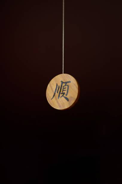 istock On a dark background, a wooden round amulet with a hieroglyph. 1215999159