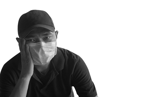 Black and white image of an Asian man wearing a surgical mask sitting on his head, worried about the Covid-19 virus. The concept of prevention of Covid disease-19