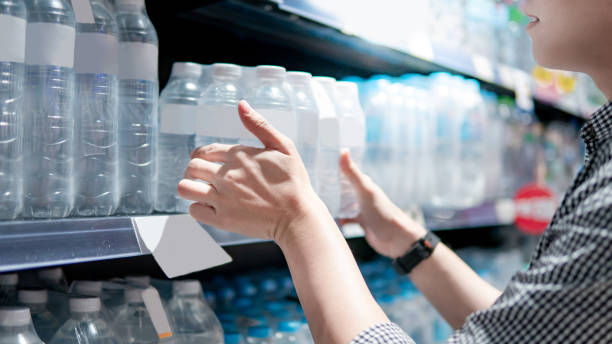 istock Shopper picking pack of water bottle from shelf 1216000231
