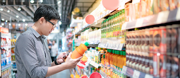 Hombre asiático comprando jugo de naranja usando el teléfono photo