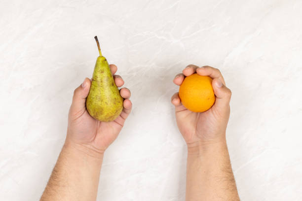 istock Hands holds pear and orange above grey marble background 1216002026