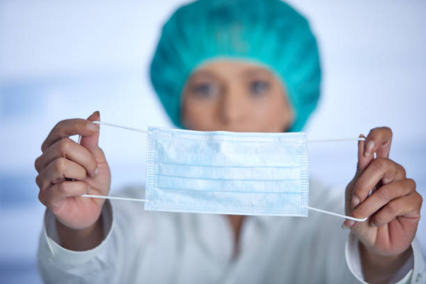 Middle aged woman in healthcare uniform and mask looking at camera