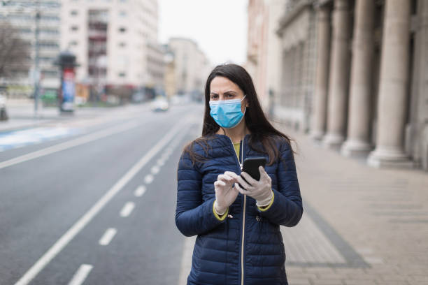 istock Young woman with a face protective mask using phone 1216006828