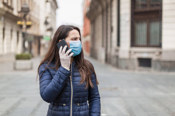 istock Young woman with a face protective mask using phone 1216007060