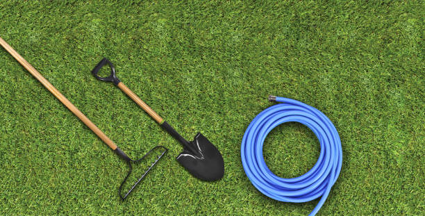 top view of gardening tools, hose, shovel & rake on a grass