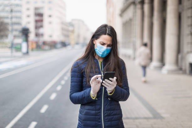 istock Young woman with a face protective mask using phone 1216007195