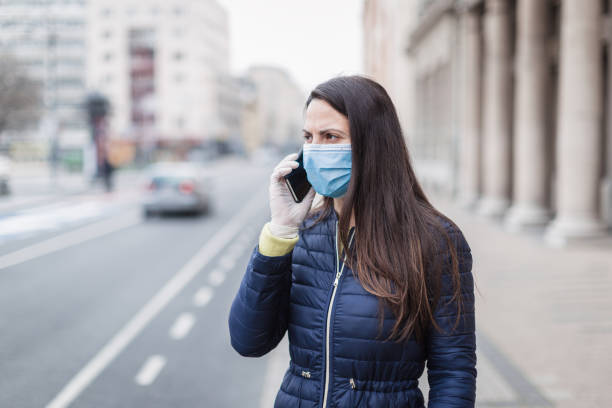 istock Young woman with a face protective mask using phone 1216007251