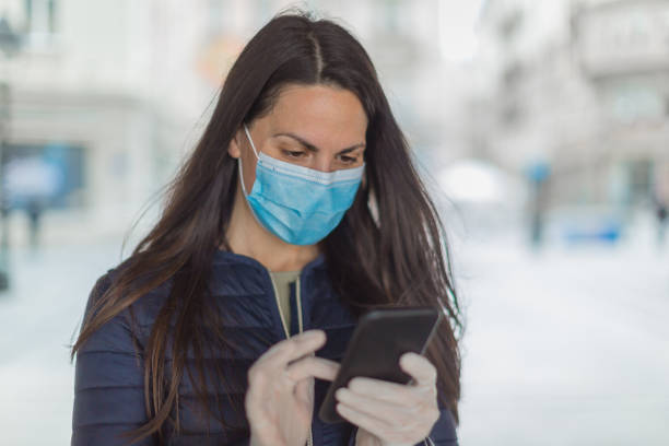 istock Young woman with a face protective mask using phone 1216007261