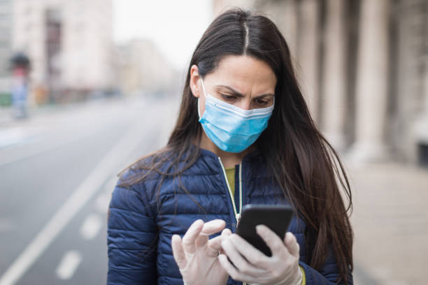 istock Young woman with a face protective mask using phone 1216007402