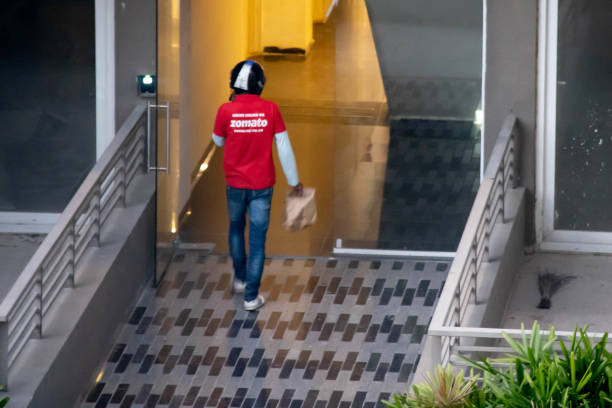 zomato consegna persona che indossa la camicia rossa e porta una borsa per la consegna a domicilio di cibo dalla startup indiana e-com - image title foto e immagini stock