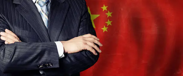Politician crossed arms of on China flag background