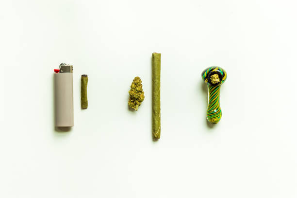 Simple marijuana flat lay. Marijuana flower, blunt, packed smoking bowl, weed roach and a lighter. stock photo