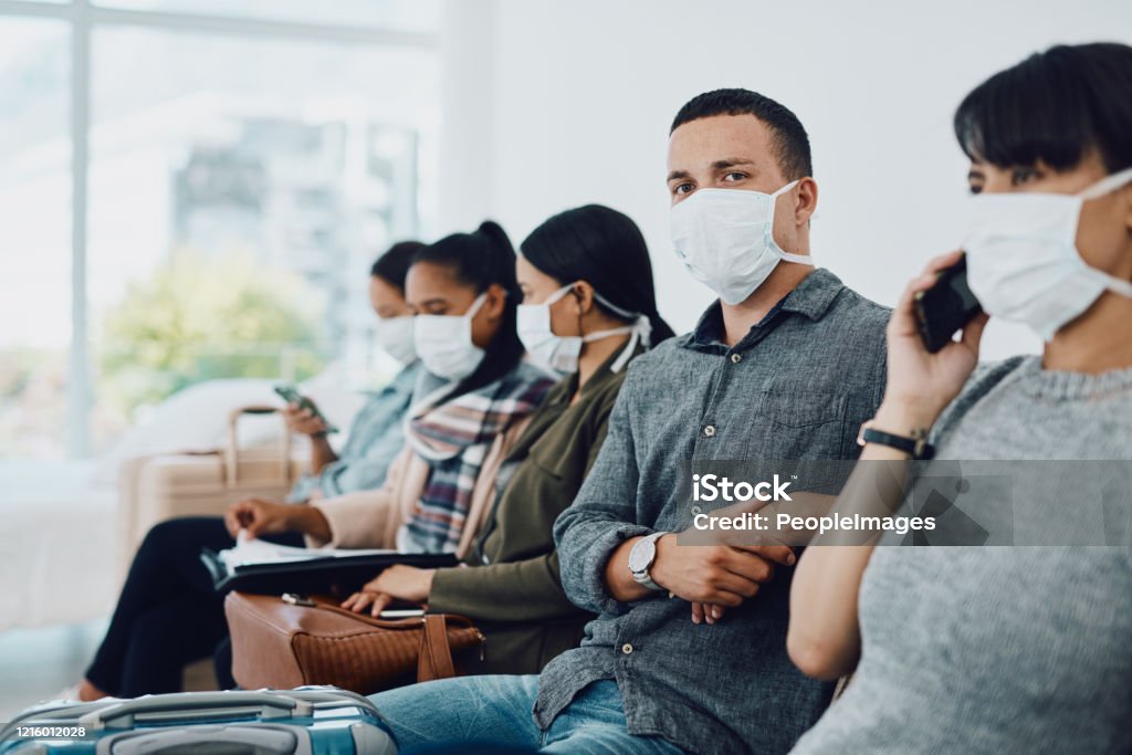Never underestimate the importance of patience Shot of a group of young people wearing masks in a waiting room Protective Face Mask Stock Photo