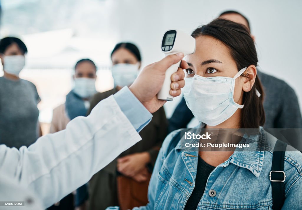 Will it be quarantine for you? Shot of a young woman getting her temperature taken with an infrared thermometer by a doctor during an outbreak Coronavirus Stock Photo