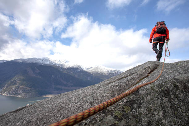 istock Mountaineer walks along mountain ridge with climbing rope 1216013640