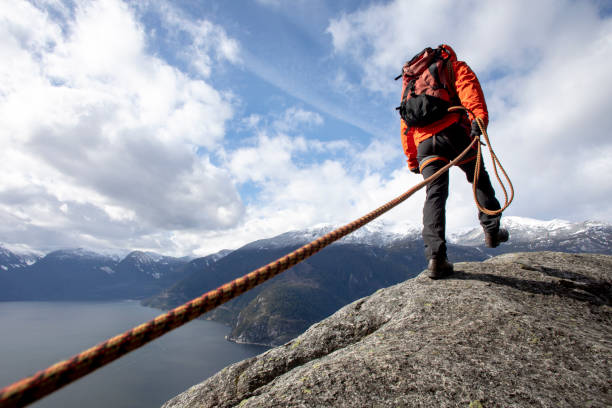 Mountaineer walks along mountain ridge with climbing rope