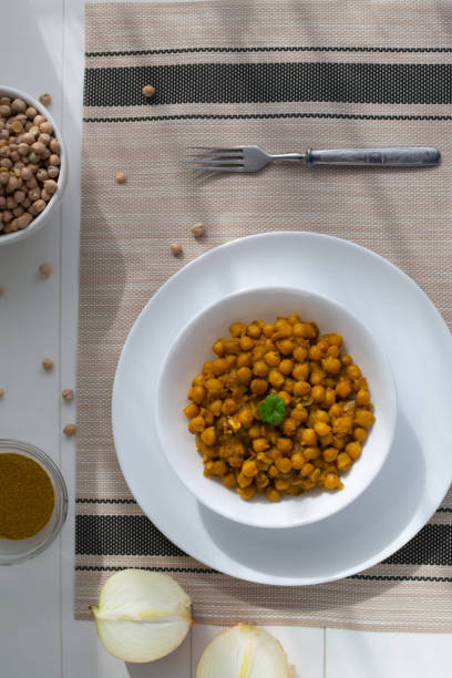istock Braised chickpeas with onions and curry in a white plate on a light background. Vegetarian food. Healthy eating 1216014812