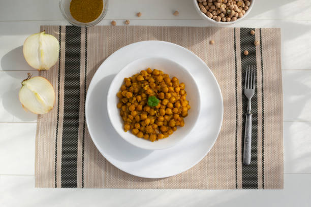 istock Braised chickpeas with onions and curry in a white plate on a light background. Vegetarian food. Healthy eating 1216014814