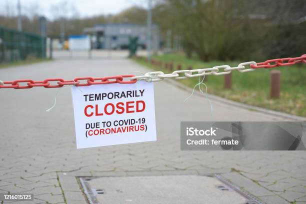 Red White Chain Barrier And Sign With Text Temporarily Closed Due To Covid19 Coronavirus In Front Of A Blurred Company Countrywide Pandemic Lock Down Copy Space Stock Photo - Download Image Now