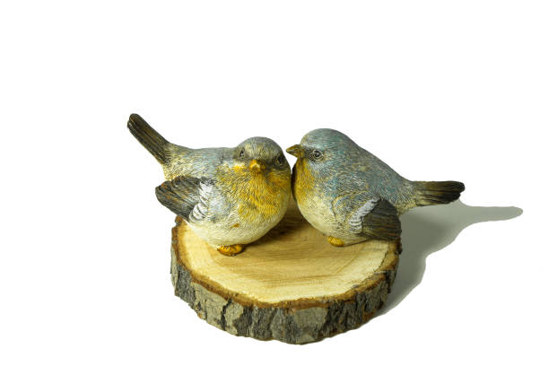 istock wo ceramic small grey and yellow birds sit on a natural birch saw cut isolated on white 1216017628