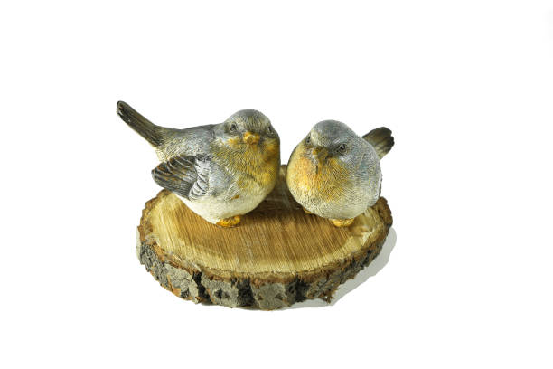 wo ceramic small grey and yellow birds sit on a natural birch saw cut isolated on white