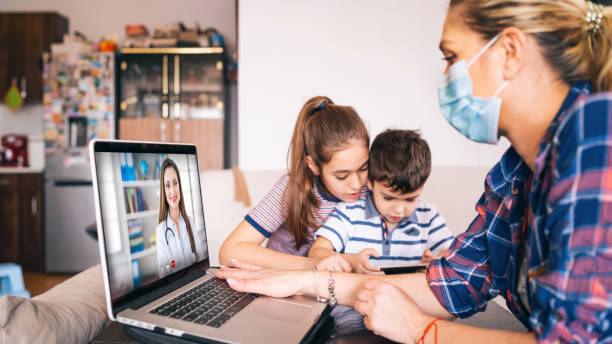madre tratando de hablar con el médico en la computadora portátil mientras mira a dos niños - child digital tablet mother teaching fotografías e imágenes de stock