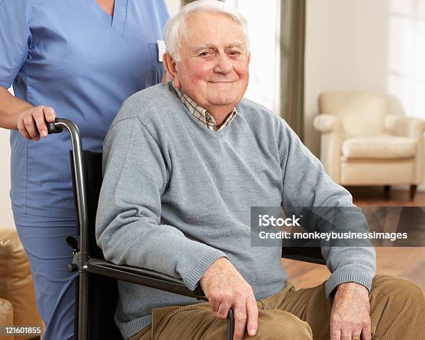 Disabled Senior Man Sitting In Wheelchair With Carer Stock Photo - Download Image Now