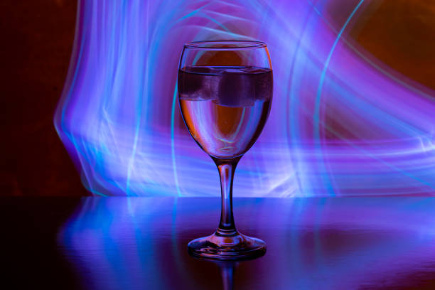 wine glass with ice on black background with neon light paintings behind