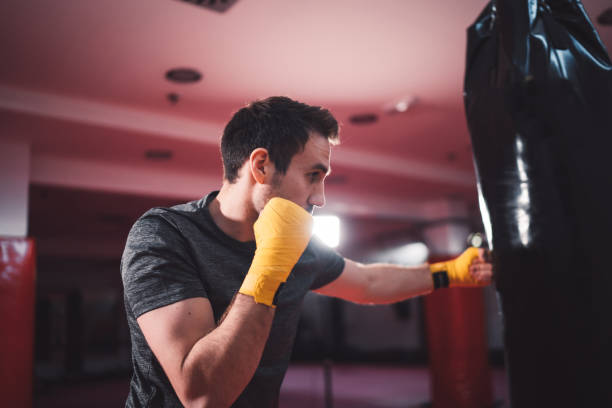 istock Caucasian man punching a punching bag at boxing studio 1216029094