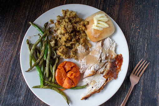 plated flat lay white turkey meat with vegetable sides, buttered bread, and gravey