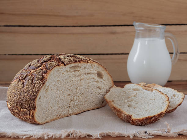 istock Freshly baked bread sliced on rustic table. Jug with fresh milk, concept breakfast. Close-up, horizontal orientation. 1216030513