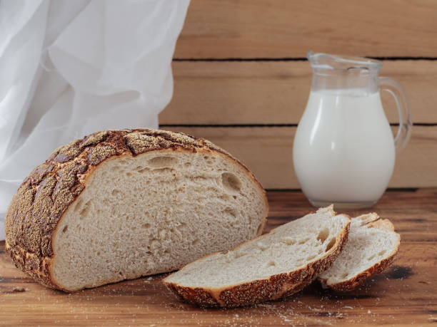 istock Freshly baked bread sliced on rustic table. Jug with fresh milk, concept breakfast. Close-up, horizontal orientation. 1216030564