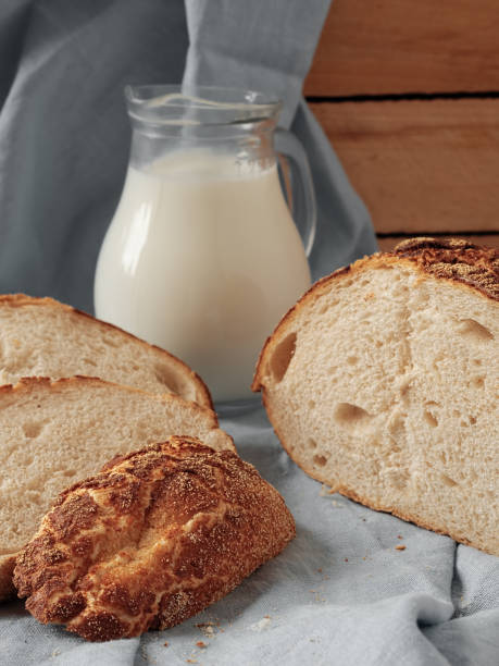 istock Freshly baked bread sliced on rustic table. Jug with fresh milk, concept breakfast. Close-up, vertical orientation. 1216030580