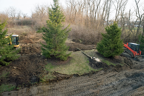 Aerial view of land being excavated with felling of deciduous trees.