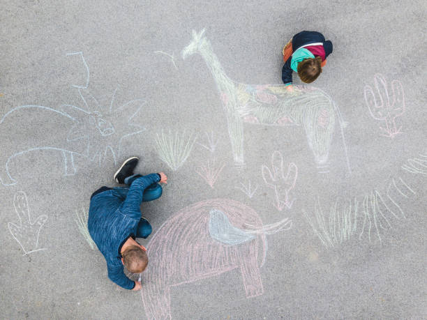 istock Young kid and his father drawing on the asphalt with chalk 1216031005