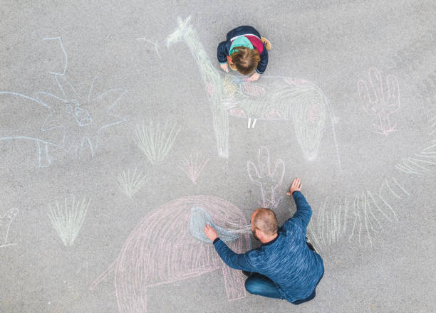 istock Young kid and his father drawing on the asphalt with chalk 1216031009