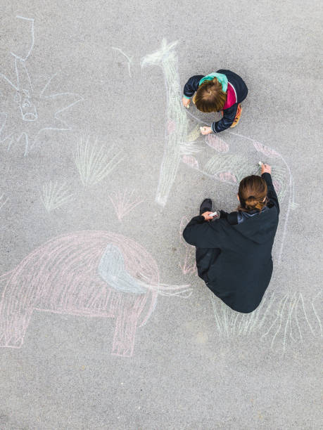 istock Young kid and his mother drawing on asphalt with chalk 1216031054