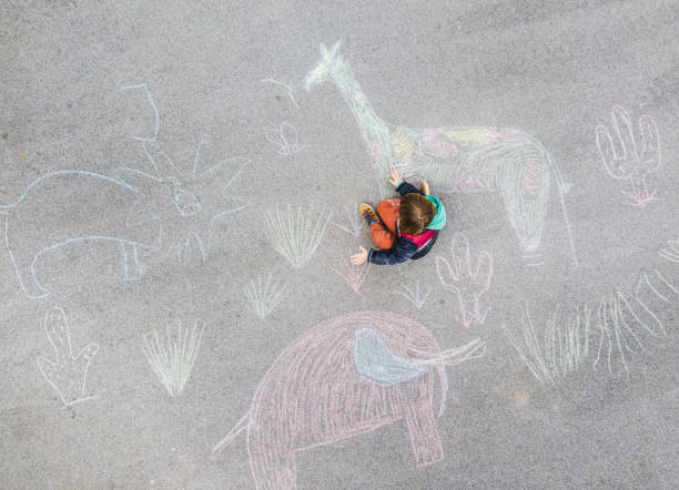 istock Young kid drawing on the asphalt with chalk 1216031577